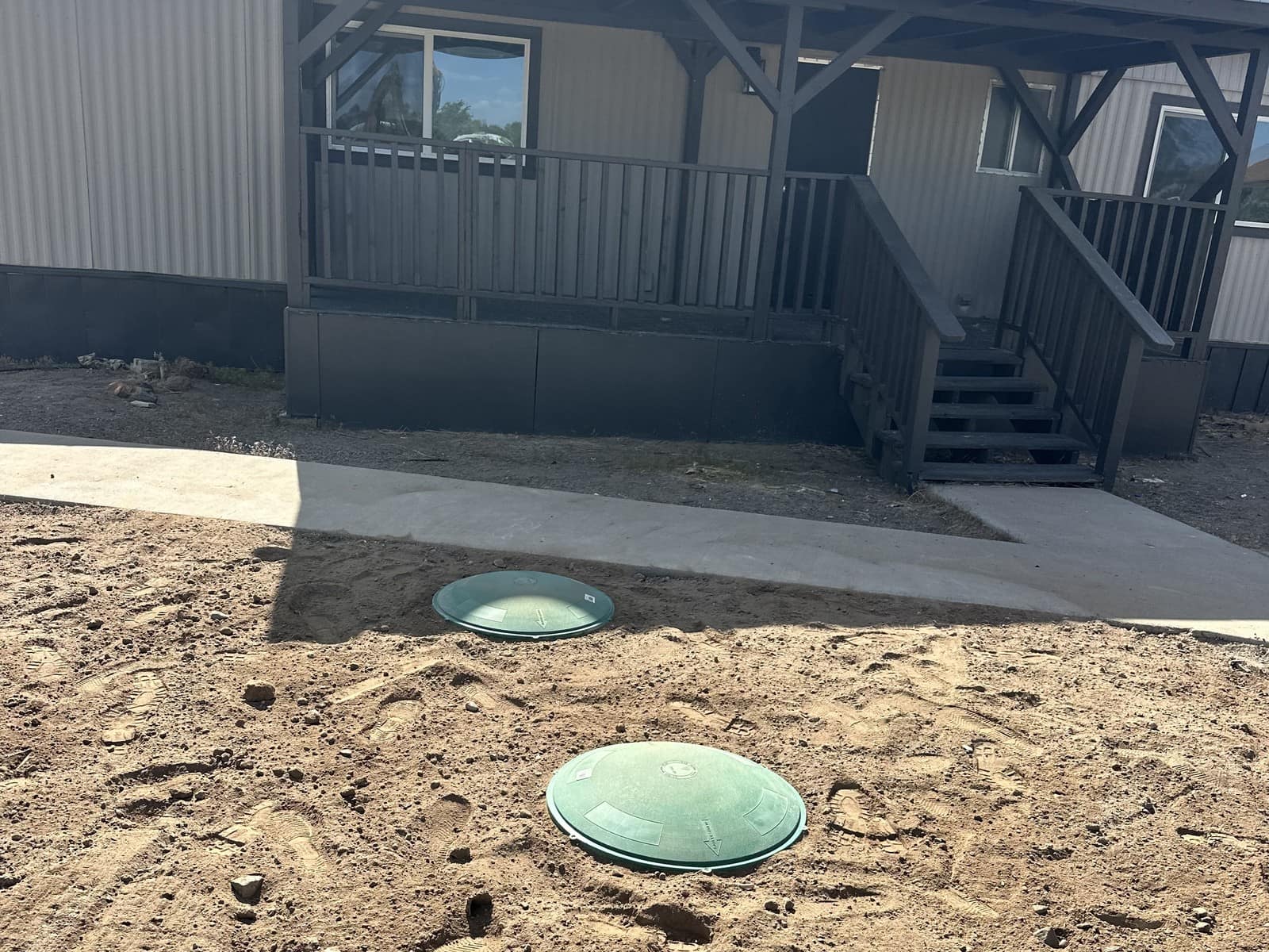 Completed residential septic install, two green Tuf-Tite riser lids set at grade in fresh dirt